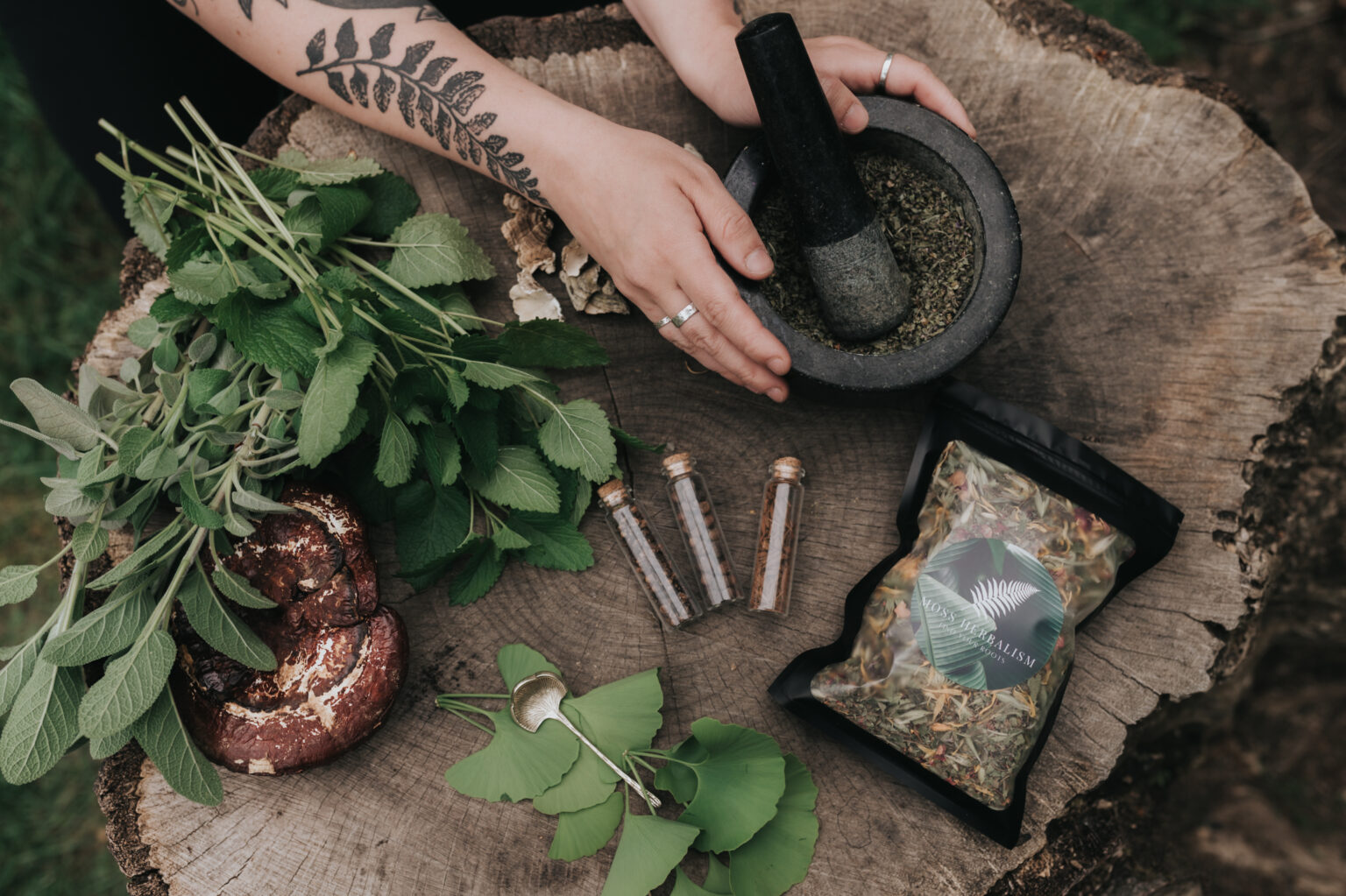 Cassidy Moss grinding herbs in a mortar on an old tree stump