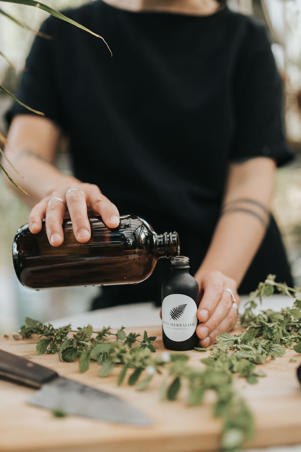 MossHerbalism_7-12-23_15 Cassidy Moss pouring a tincture over fresh herbs